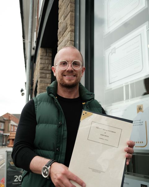 A Kingswood will writing adviser holding a completed last will and testament outside the Anstey office